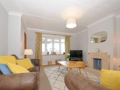 A living room with brown sofas yellow and blue cushions a wooden coffee table a fireplace and a television at Sea Spray in Port Isaac