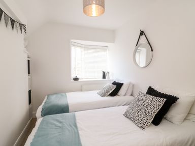 A bedroom with two single beds blue blankets and black and white pillows at Bayview Loft in Weymouth