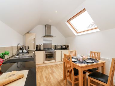 A kitchen with wooden flooring dining table and chairs stove sink and skylight window at Bayview Loft in Weymouth