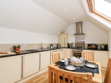 A kitchen with dining table set with plates and cups and modern appliances at Bayview Loft in Weymouth