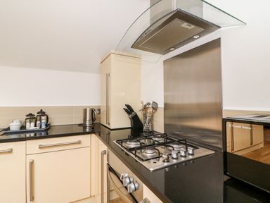 A kitchen with a gas stove oven microwave electric kettle and kitchen utensils at Bayview Loft in Weymouth