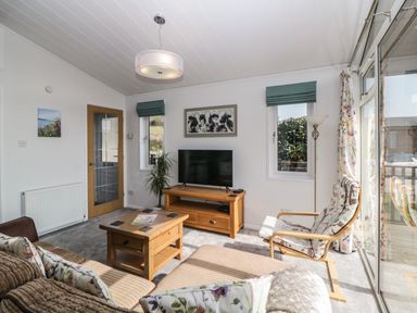 A living room with a wooden coffee table sofa and television at Meadow Lodge in Newton Ferrers