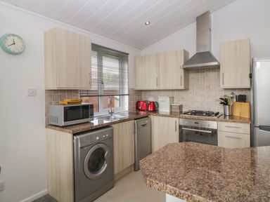 A kitchen with a washing machine microwave sink and oven at Meadow Lodge in Newton Ferrers