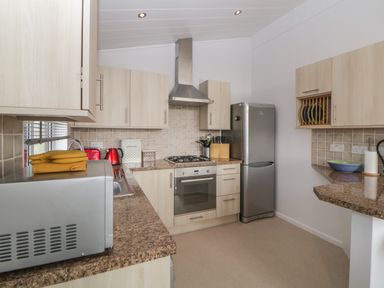 A kitchen with wooden cabinets stainless steel refrigerator microwave oven and kettle at Meadow Lodge in Newton Ferrers