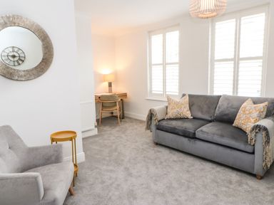 A living room with a sofa and armchair and a small desk with a lamp at Toll House in Corbridge