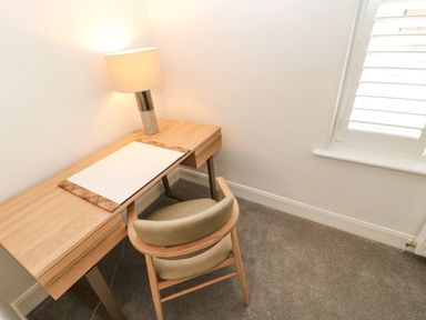 A wooden desk with a table lamp and a chair in a small room with a window at Toll House in Corbridge
