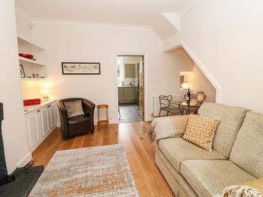 A living room with a beige sofa a brown chair wooden floor and a small dining table with chairs at Toll House in Corbridge