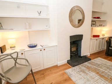 A room with built in shelves a small fireplace and a chair at Toll House in Corbridge