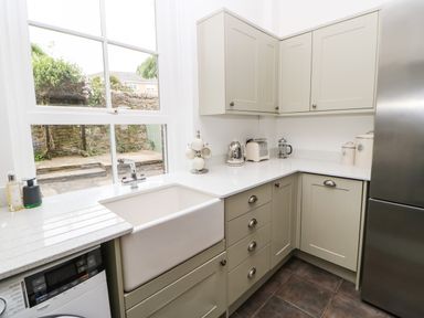 A kitchen with a white sink under a window beige cabinets and a silver refrigerator at Toll House in Corbridge
