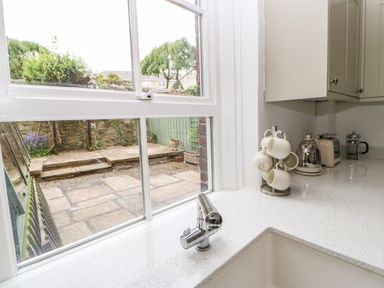 A kitchen sink area with a faucet mugs on a stand kettle toaster and French press on the counter at Toll House in Corbridge