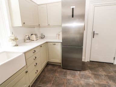 A kitchen corner with grey cabinets a stainless steel fridge and countertop appliances at Toll House in Corbridge