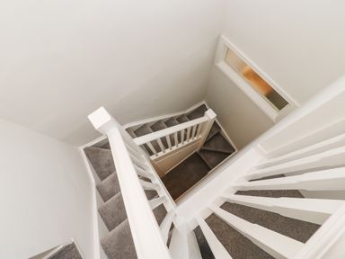 A carpeted staircase with white railings and a small window at Toll House in Corbridge