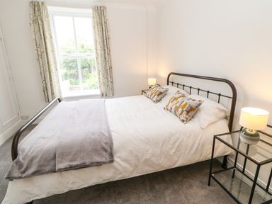 A bedroom with a double bed two bedside tables with lamps and a window with curtains at Toll House in Corbridge