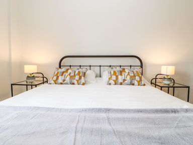 A bedroom with a bed with white and patterned pillows and two bedside tables with lamps at Toll House in Corbridge