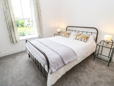 A bedroom with a double bed with patterned pillows and lamps on bedside tables at Toll House in Corbridge