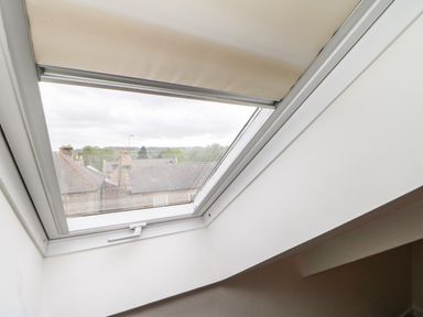 A skylight window with a partially closed blind showing rooftops outside at Toll House in Corbridge