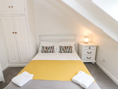 A bedroom with a double bed a bedside table with lamp and built in wardrobes at Toll House in Corbridge