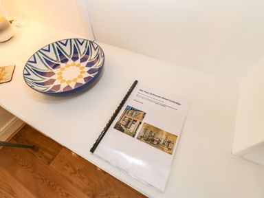 A white table with a patterned bowl and an information booklet at Toll House in Corbridge