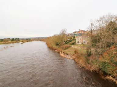 A river flowing beside houses and trees at Toll House in Corbridge