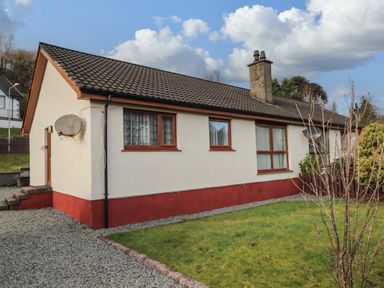 A bungalow with a satellite dish and a grassy front yard at The Hideout in Portree