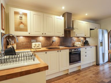 A kitchen with wooden countertops white cabinets a stainless steel oven and refrigerator at The Hideout in Portree