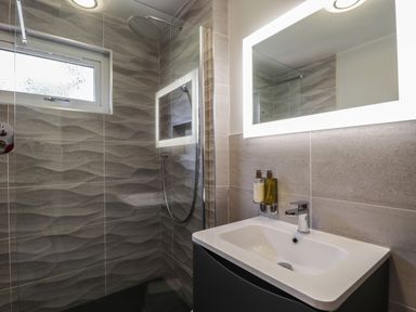 A bathroom with a shower area and a sink with a mirror at The Hideout in Portree