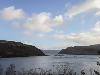A body of water between two hills under a partly cloudy sky at The Hideout in Portree