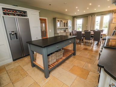 A kitchen with a large island table a refrigerator a dining table with chairs and a cabinet at Fontburn Farmhouse Ewesley near Rothbury