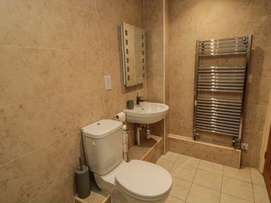 A bathroom with a toilet sink mirror and heated towel rail at Fontburn Farmhouse in Ewesley near Rothbury