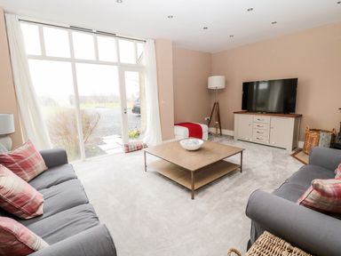 A living room with two sofas and a coffee table in front of a large window at Fontburn Farmhouse in Ewesley near Rothbury