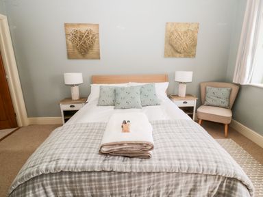 A bedroom with a bed and two bedside tables with lamps at Fontburn Farmhouse Ewesley near Rothbury
