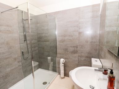 A bathroom with a shower, toilet, sink, and a bottle of soap at Fontburn Farmhouse in Ewesley near Rothbury