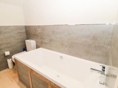 A bathroom with a bathtub toilet and toilet paper holder at Fontburn Farmhouse in Ewesley near Rothbury