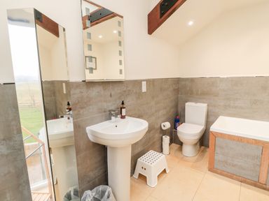 A bathroom with a sink a toilet a bathtub and a small white step stool at Fontburn Farmhouse in Ewesley near Rothbury