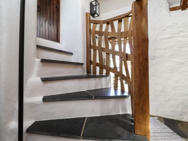 A stone staircase with wooden railing and white plaster walls at Y Felin at Coed Cadw in Felindre Farchog near Newport Pembrokeshire
