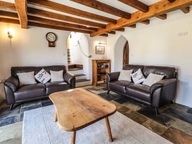 A living room with two sofas a wooden coffee table and a wall clock at Y Felin at Coed Cadw Felindre Farchog near Newport Pembrokeshire