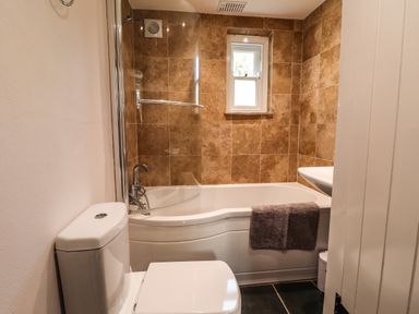 A bathroom with a toilet bathtub with a towel and a window above at Y Felin at Coed Cadw in Felindre Farchog near Newport Pembrokeshire
