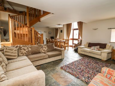 A living room with sofas stairs a dining table and a colorful rug at Maes Y Berllan Barn in Gilwern