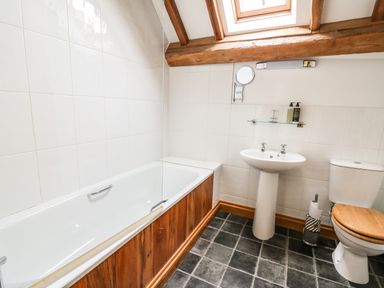 A bathroom with a bathtub wooden panel sink toilet and skylight at Maes Y Berllan Barn in Gilwern
