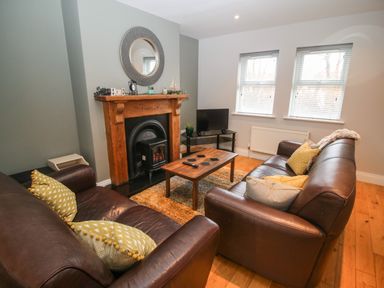 A living room with two brown leather sofas a wooden coffee table a fireplace and a TV at Pebble Lodge in Kenmare County Kerry