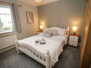 A bedroom with a white bed and white bedside tables with lamps at Pebble Lodge in Kenmare County Kerry