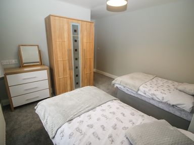A bedroom with two single beds a wooden wardrobe and a chest of drawers with a mirror at Pebble Lodge in Kenmare County Kerry