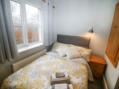 A bedroom with a double bed next to a window and a bedside table with a lamp at Pebble Lodge Kenmare County Kerry