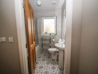 A bathroom with a pedestal sink toilet bathtub and towel rack at Pebble Lodge in Kenmare County Kerry