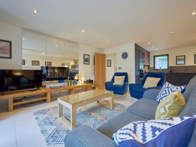 A living room with blue armchairs a gray sofa a wooden coffee table and a large TV at Riverside Park 2 in Keswick