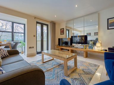 A living room with couches coffee table television and dining area at Riverside Park 2 in Keswick