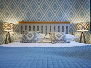 A bed with two patterned cushions and lamps on either side in a bedroom at Riverside Park 2 in Keswick