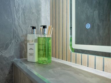 Two pump bottles of hand and body lotion and wash on a bathroom countertop next to a mirror at Riverside Park 2 in Keswick