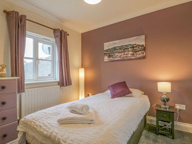 A bedroom with a single bed next to a window and bedside table with a lamp at Knapp Cottage in Chickerell