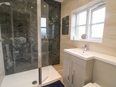 A bathroom with a glass shower enclosure vanity unit with basin window and mirror at Knapp Cottage in Chickerell